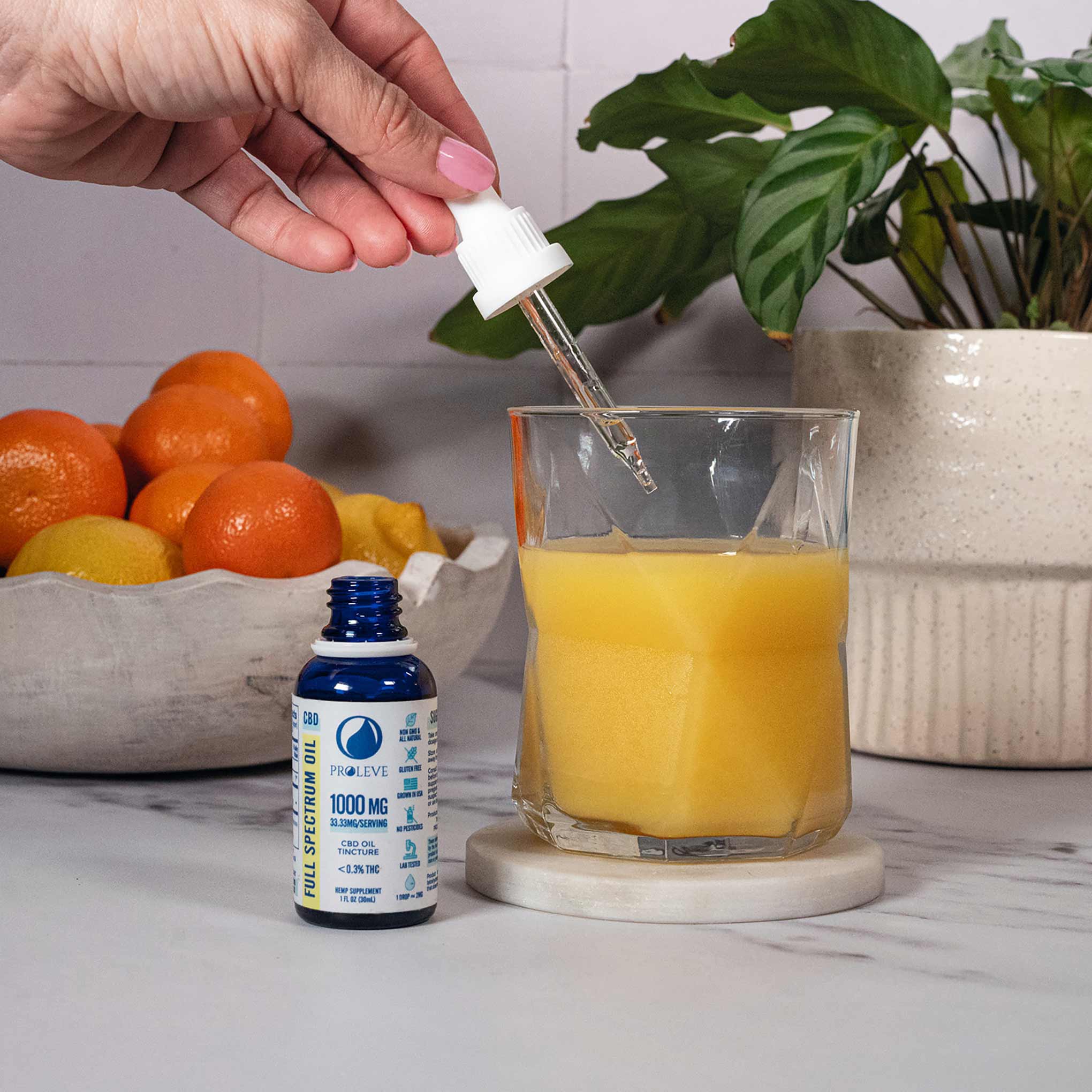 1000MG full spectrum tincture dropping into a glass of orange juice 